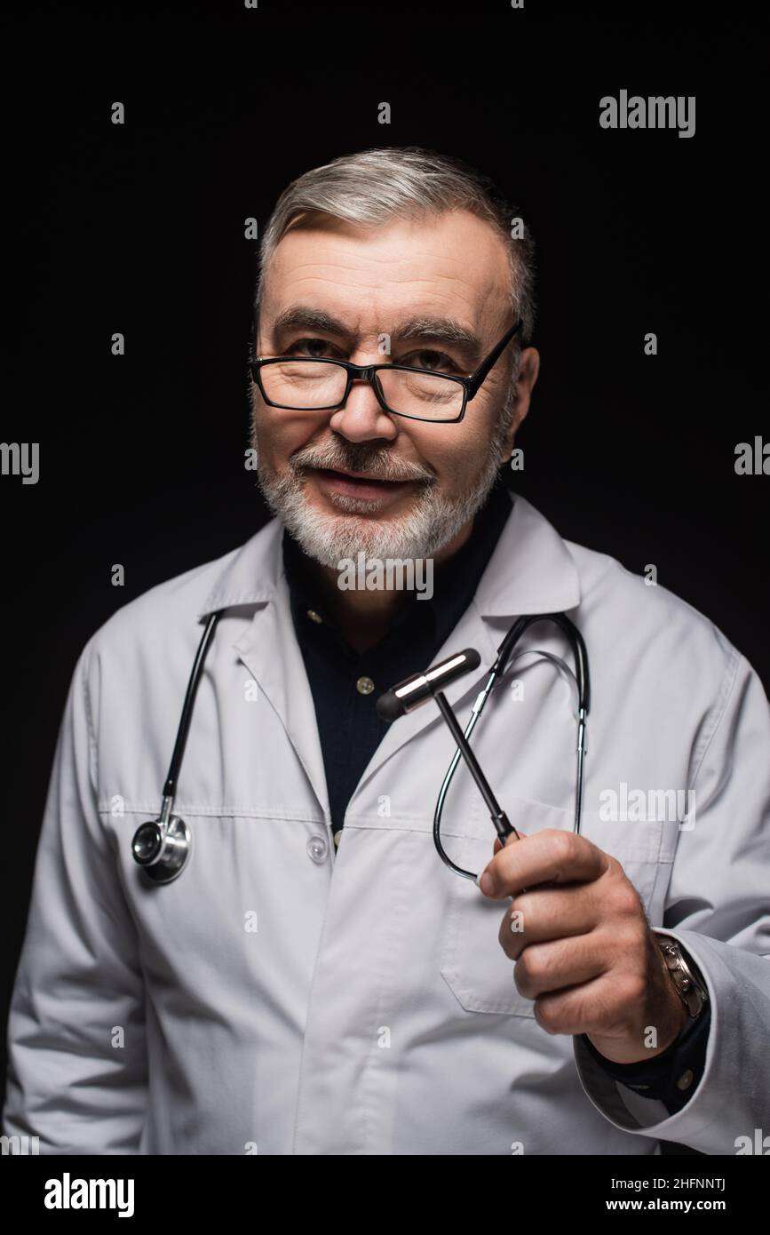 neurologue positif en manteau blanc et lunettes tenant le malléus réflexe isolé sur le noir Banque D'Images