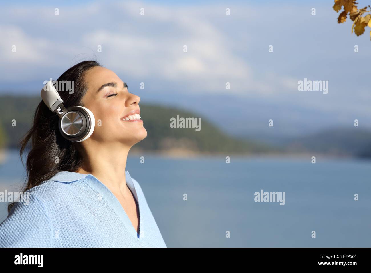 Une femme heureuse médite en portant des écouteurs sans fil dans un lac Banque D'Images