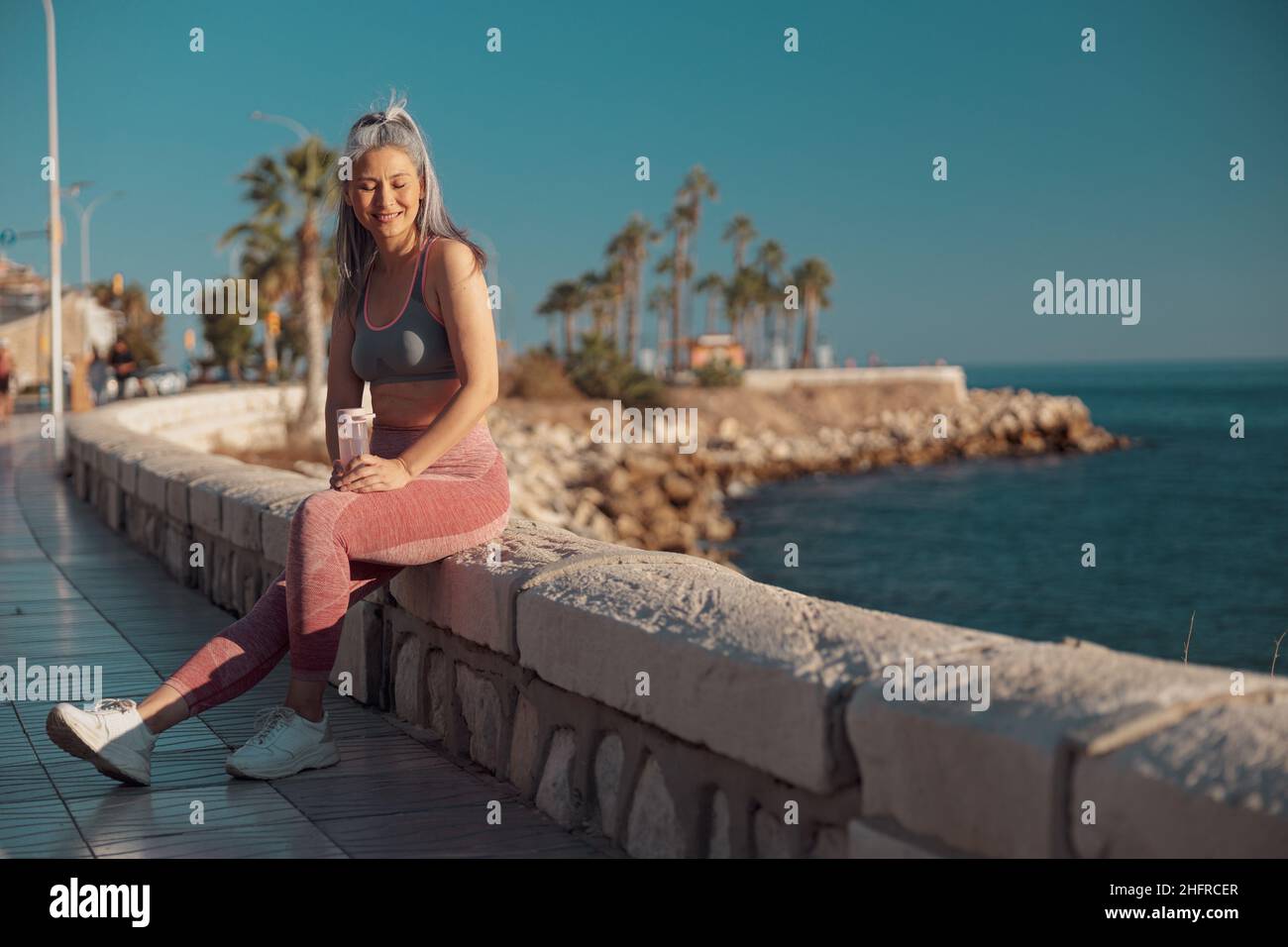 Femme adulte sportive se reposant après l'entraînement au bord de l'eau Banque D'Images