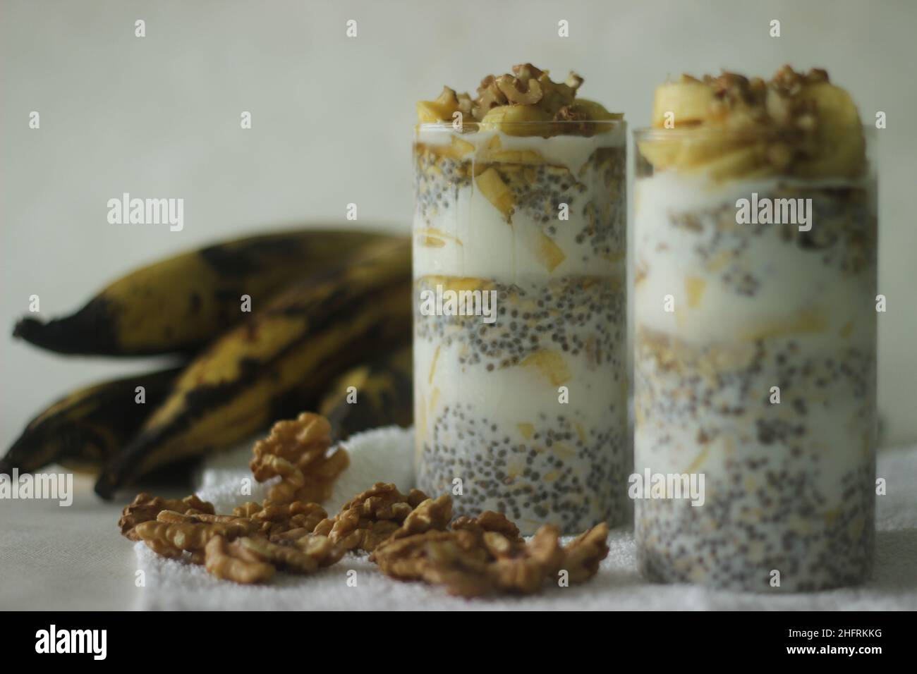 Avoine de nuit avec plantain mûr et noix.Fait en trempant des flocons d'avoine et des graines de chia dans du lait servi avec des tranches de plantains, des noix et sucré Banque D'Images