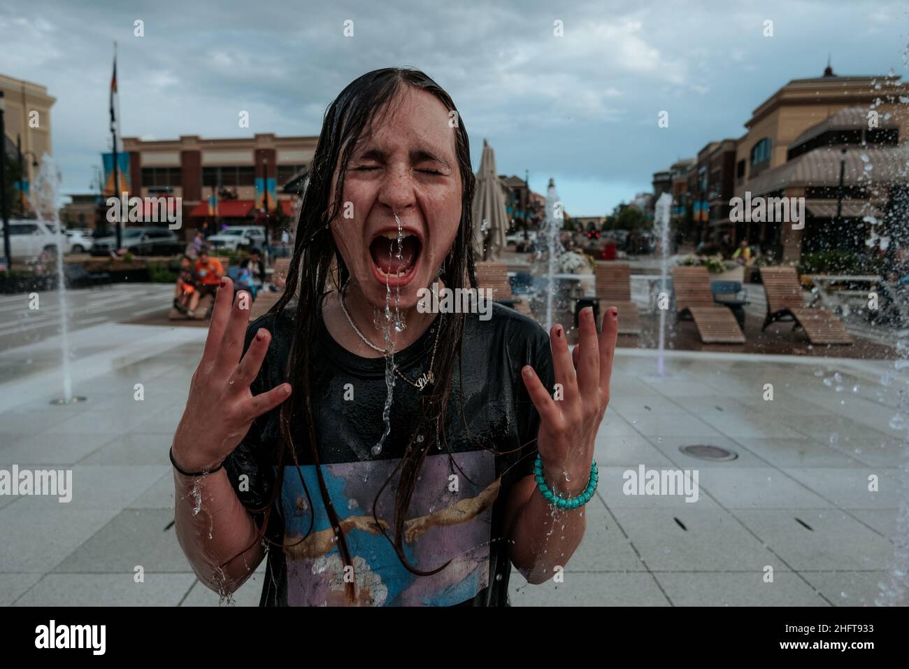 Surprise adolescente jouant dans la fontaine à l'extérieur Banque D'Images