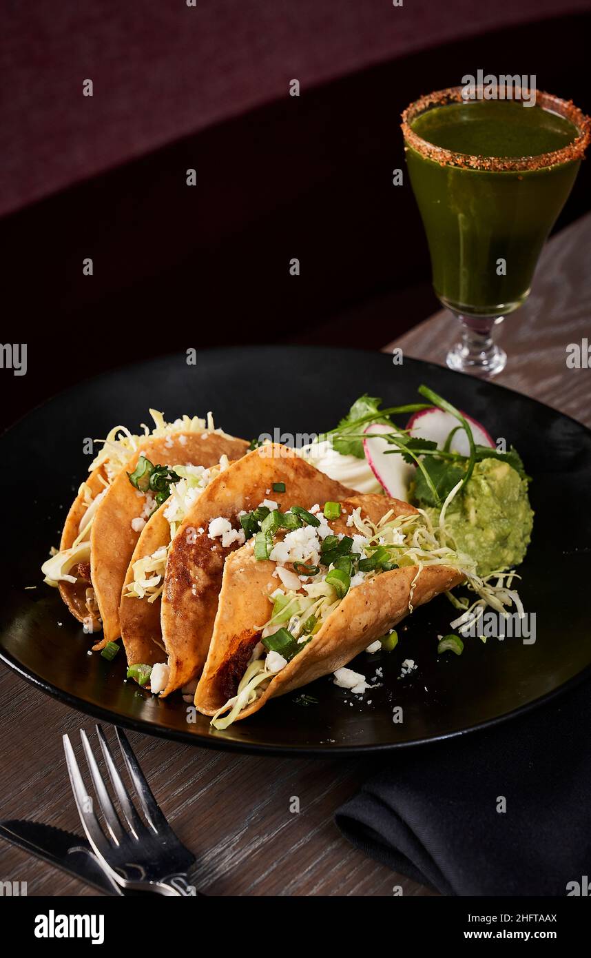 Tacos à coque dure avec guacamole et un cocktail artisanal . Banque D'Images Tacos à coque dure avec guacamole et un cocktail artisanal . Banque D'Images