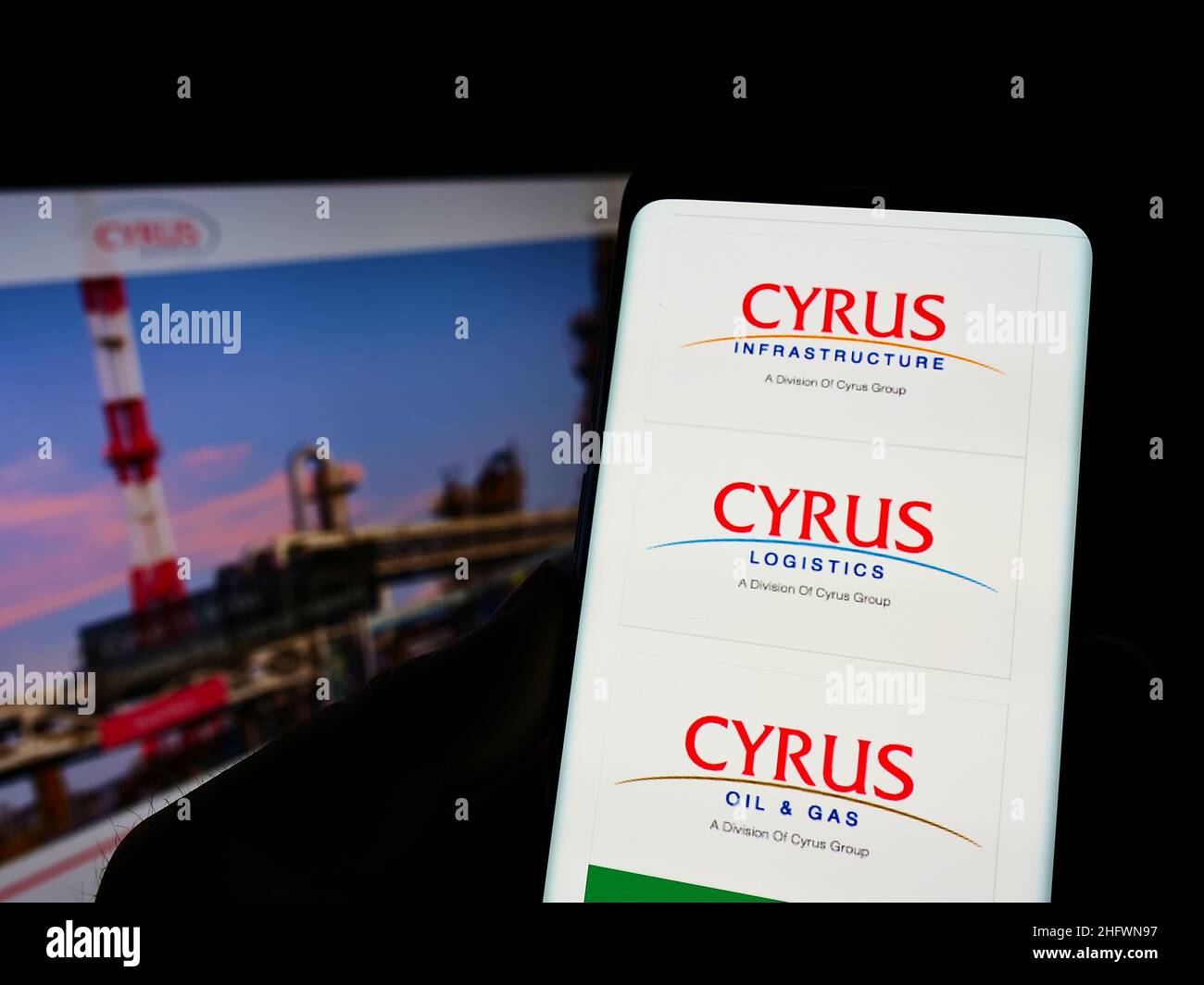 Personne tenant cellulaire avec la page web du conglomérat Cyrus Groupe de compagnies à l'écran avec des logos d'affaires.Mise au point sur l'affichage du téléphone. Banque D'Images