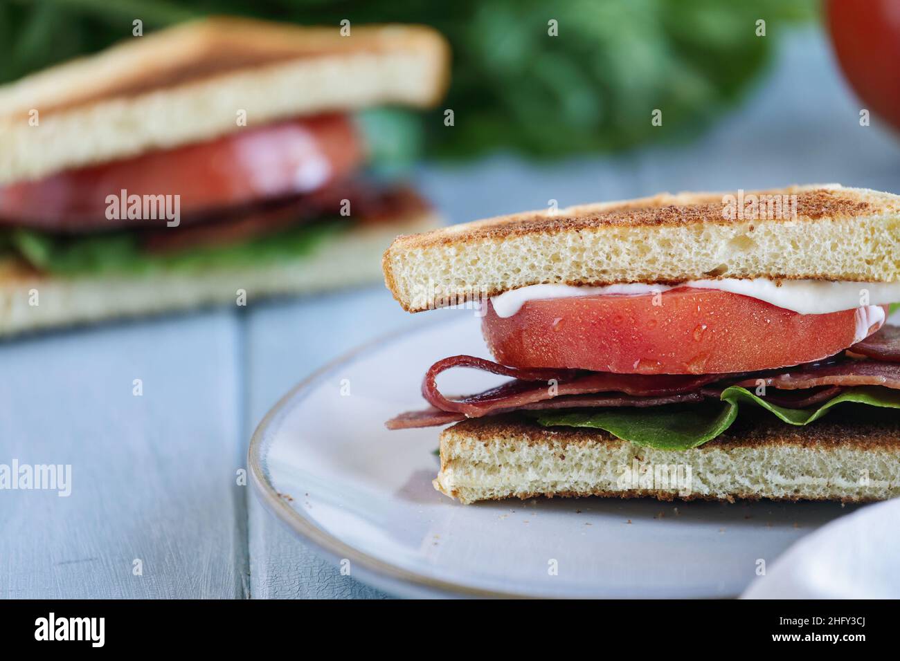 Sandwich maison au bacon, à la laitue et à la tomate sur une table rustique blanche.Mise au point sélective avec arrière-plan flou. Banque D'Images