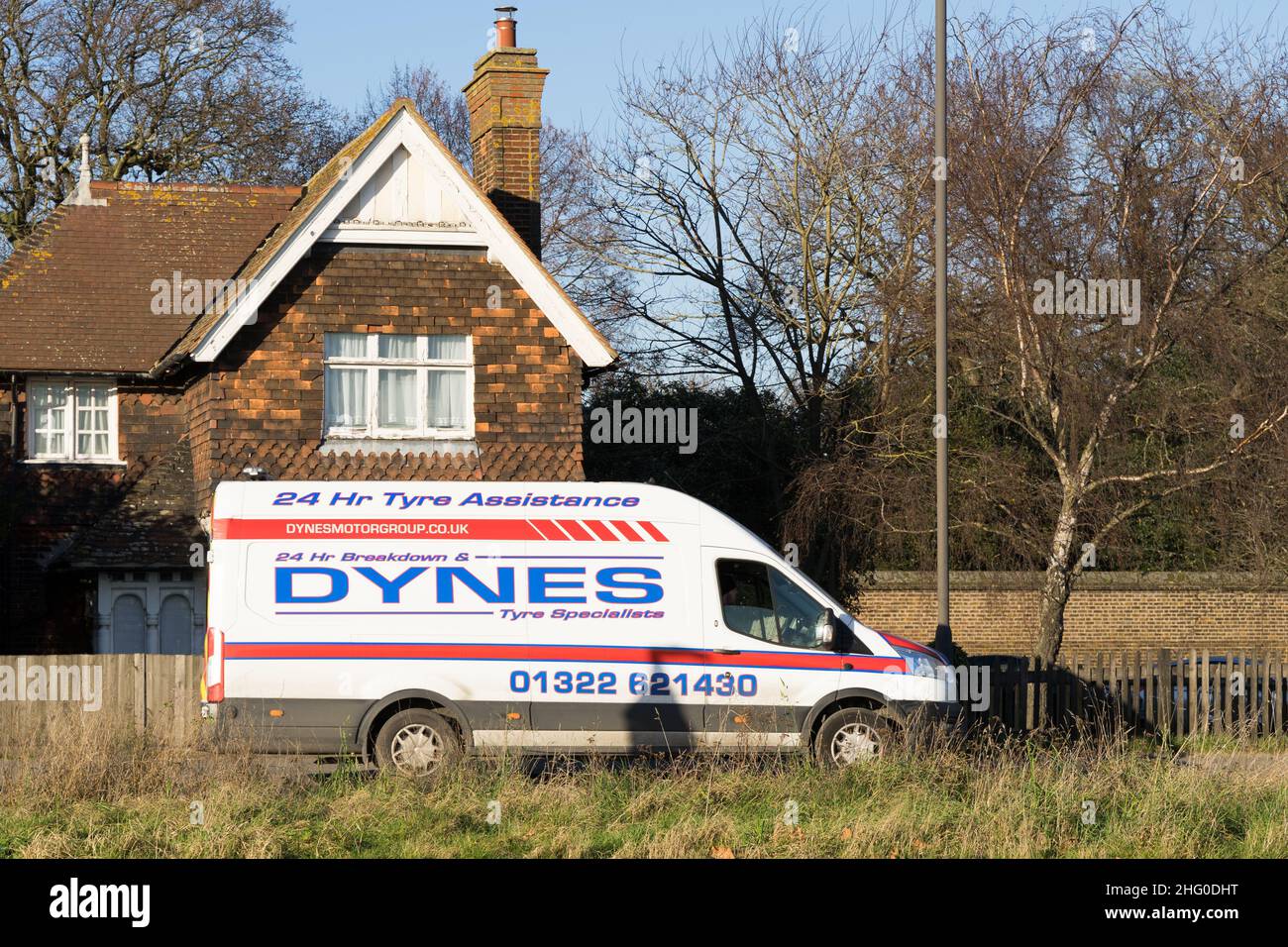 Une fourgonnette blanche fournissant 24 heures de tire assistance DYNES en route vers le client avec une maison dans l'arrière-plan Londres Angleterre Royaume-Uni Banque D'Images
