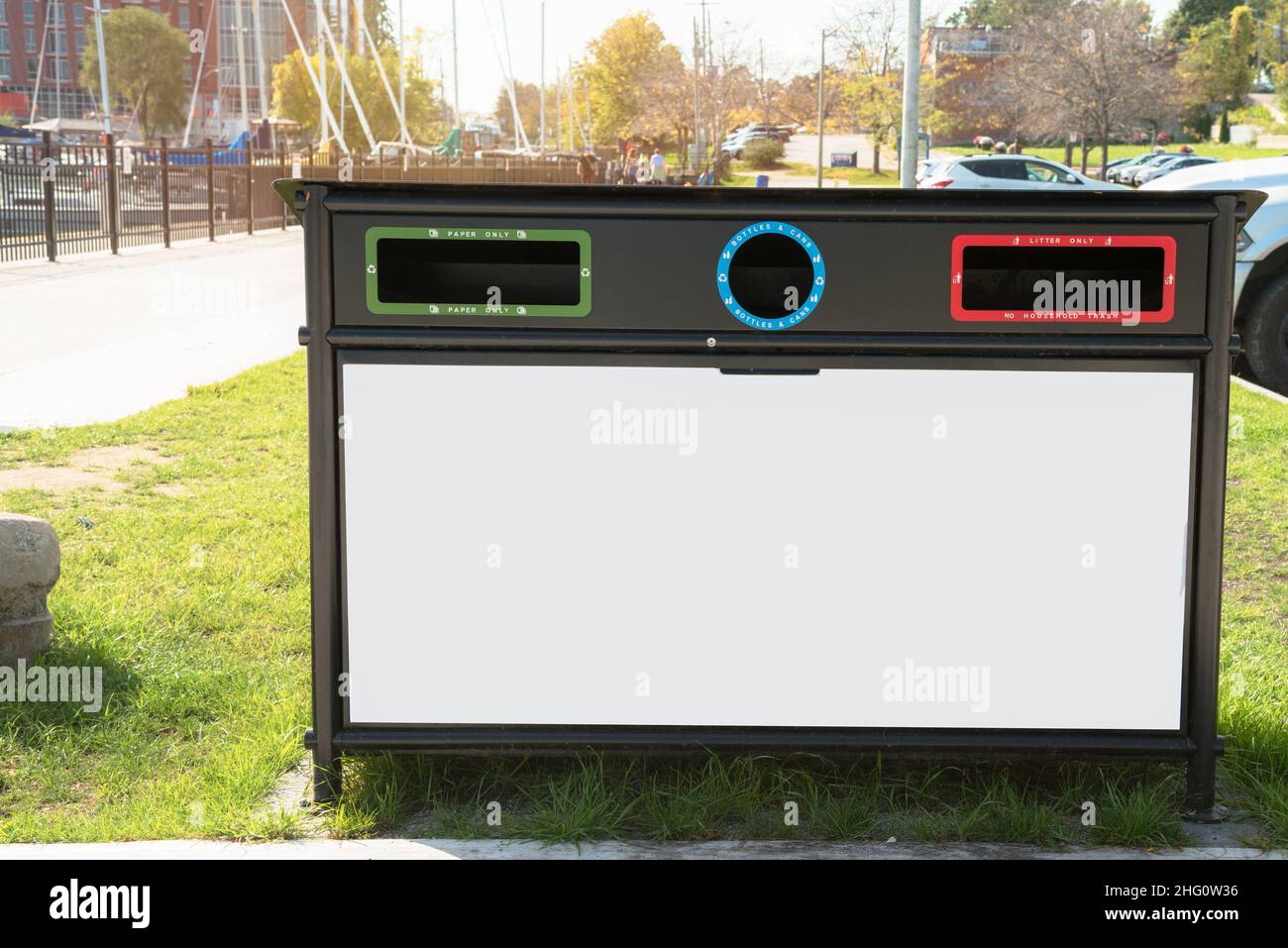 Bac de recyclage avec un panneau d'affichage vierge dans un parc public le jour d'automne ensoleillé. Copier l'espace. Banque D'Images