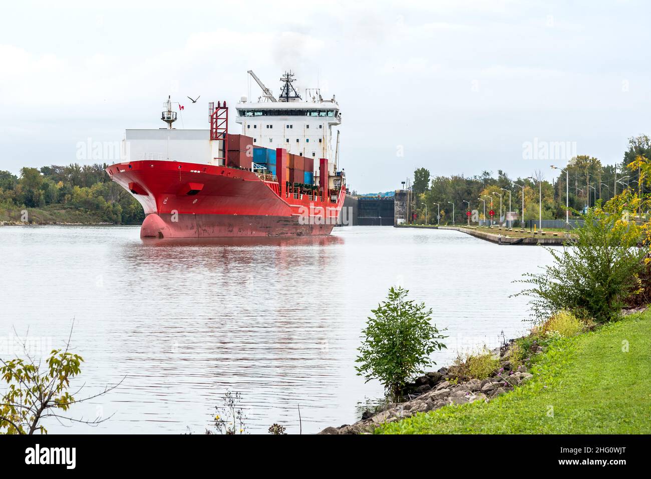Grand bateau à conteneurs naviguant sur un canal navigable lors d'une journée d'automne nuageux. Un verrou est visible en arrière-plan Banque D'Images