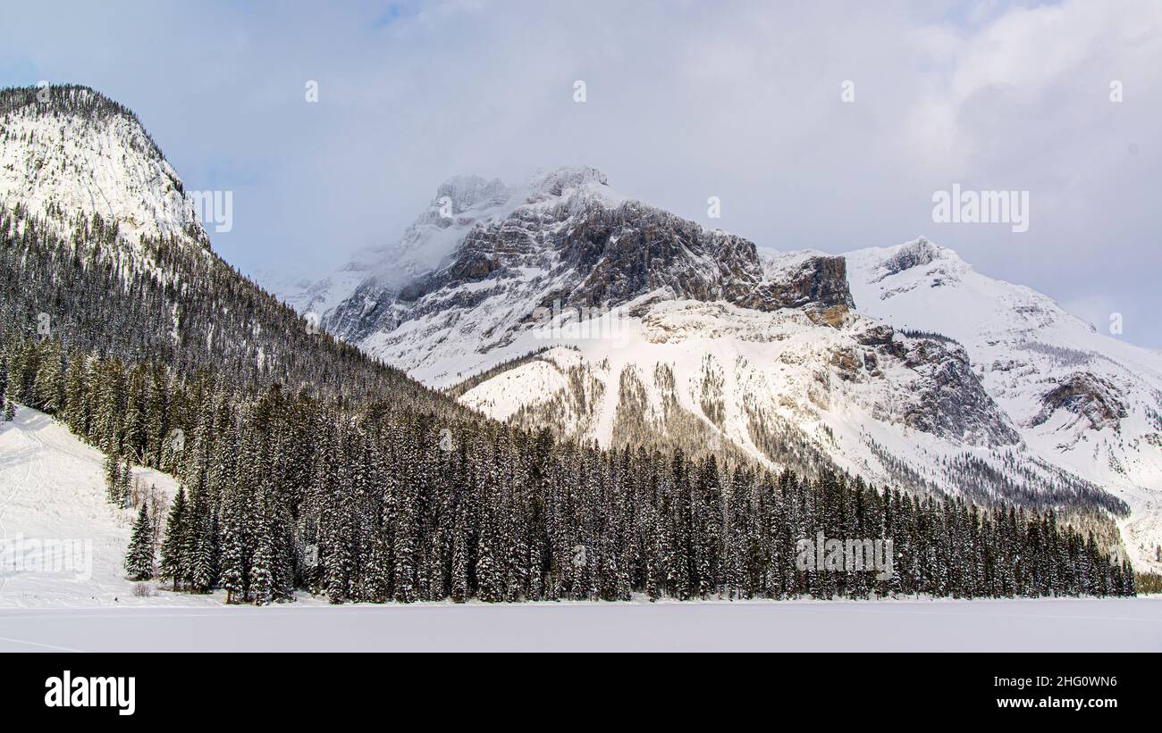 Parc national Yoho, Canada - décembre 23 2021 : le lac Emeraude gelé se cachant dans une forêt d'hiver surmontée par les montagnes rocheuses dans le parc national Yoho Banque D'Images