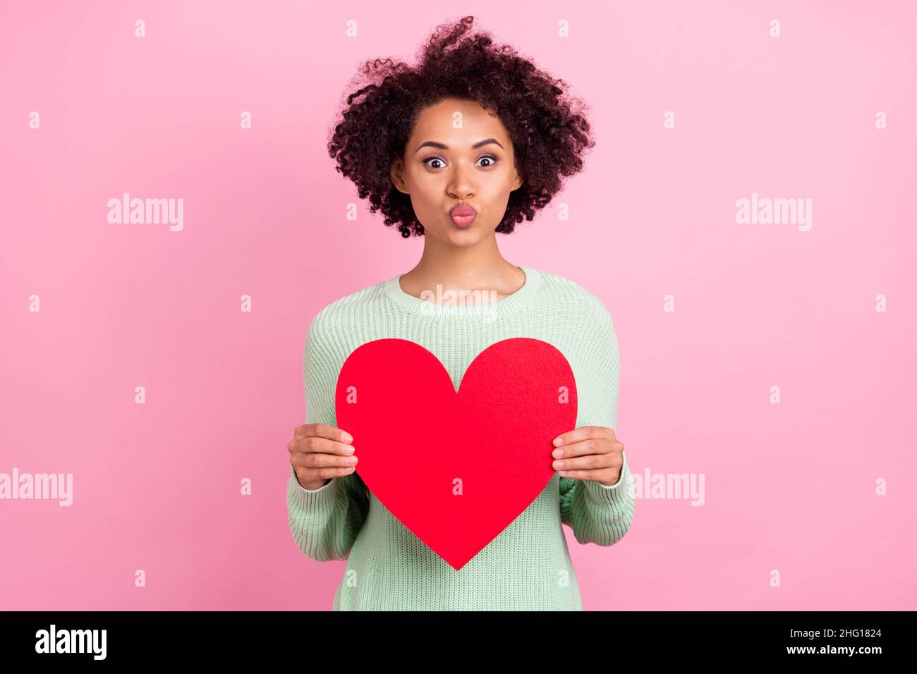 Photo d'adorable femme en peau sombre baiser lèvres tenir coeur symbole carte postale isolée sur fond de couleur rose Banque D'Images