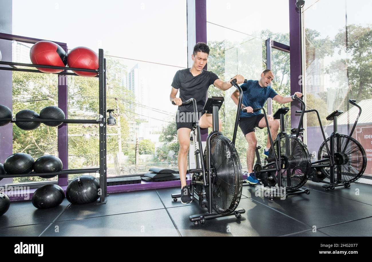 Deux hommes s'entraîner sur des vélos d'exercice à la salle de sport de Bangkok Banque D'Images