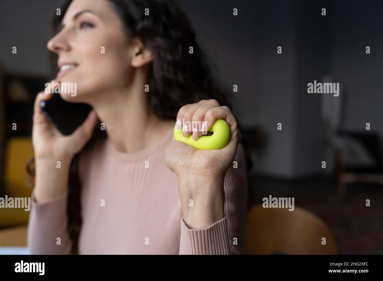 Jeune femme souriante, en train de presser la bague de serrage, de pratiquer des exercices de main et de poignet au travail Banque D'Images