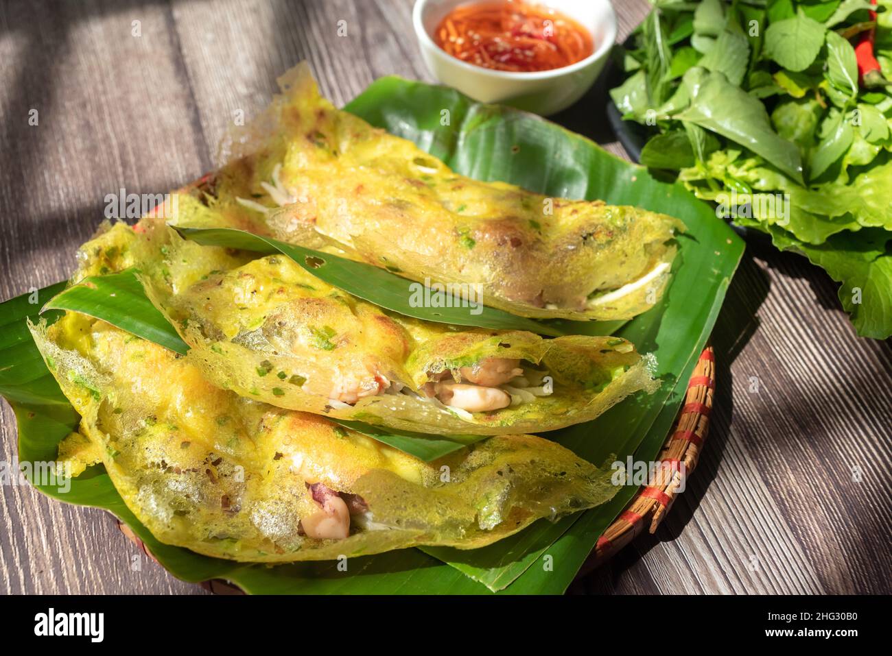 Banh Xeo est un gâteau traditionnel vietnamien.Les ingrédients du gâteau comprennent la farine, les crevettes, le porc, les tubercules tordus, le calmar... et les légumes pour accompagner le cak Banque D'Images