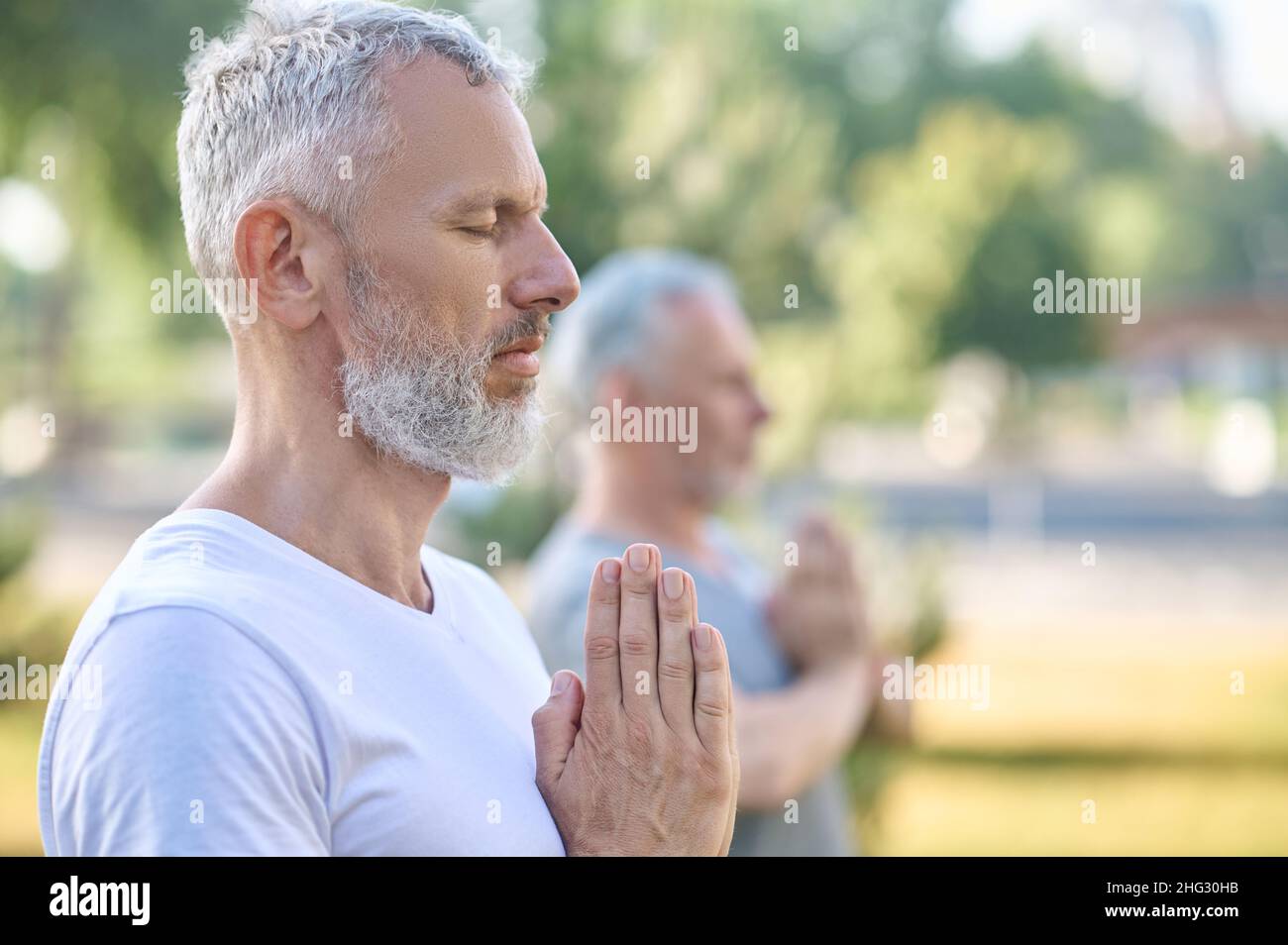 Personnes d'âge moyen ayant des cours de yoga dans le parc Banque D'Images
