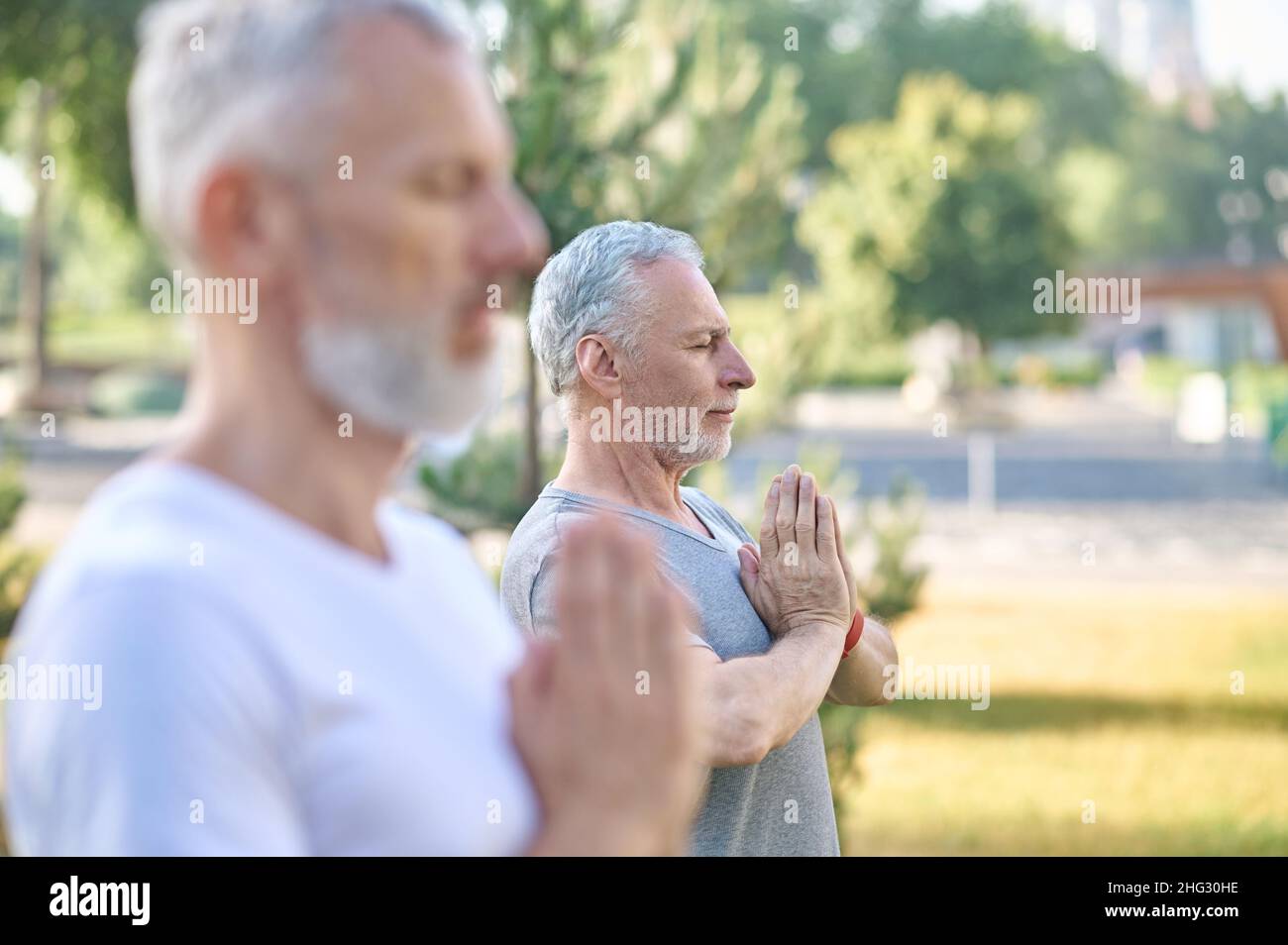 Personnes d'âge moyen ayant des cours de yoga dans le parc Banque D'Images