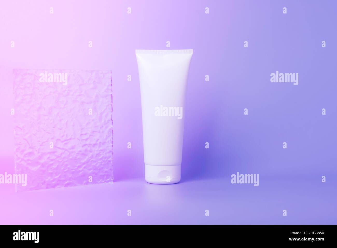 Produit cosmétique dans un tube, contenant blanc sur fond violet.Shampooing, crème pour les mains, dentifrice emballage blanc Banque D'Images