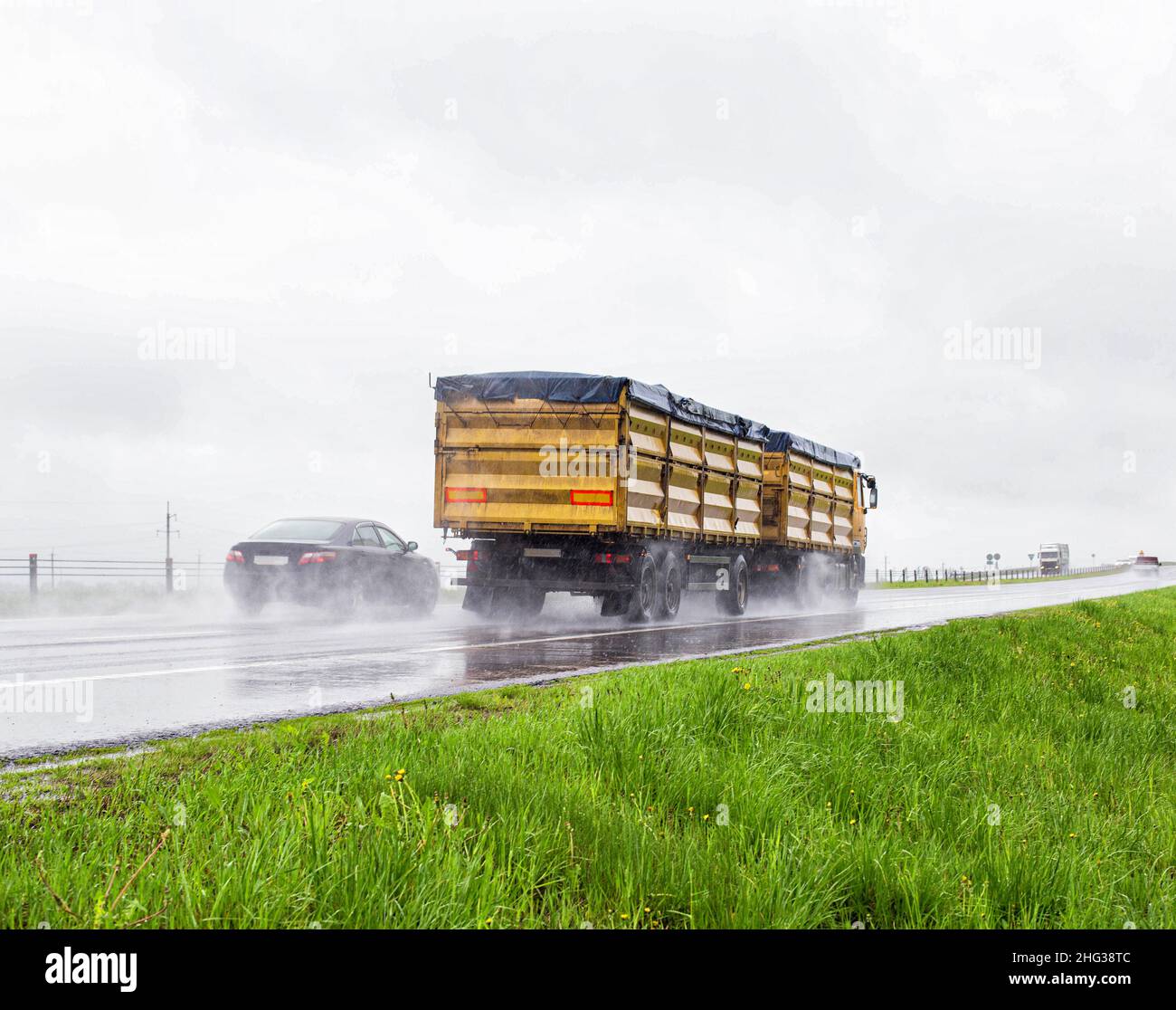 Camion à grains jaune moderne avec remorque transporter le grain dans le mauvais temps pluvieux grain sur la route en été.Concept d'comptabilité, espace de copie pour le texte, tr Banque D'Images