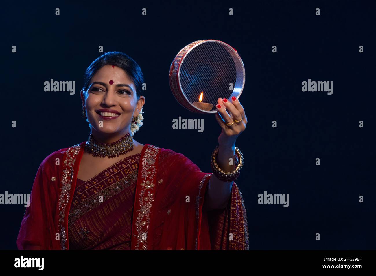 Femme tenant un tamis et souriant à l'occasion de Karva Chauth Banque D'Images