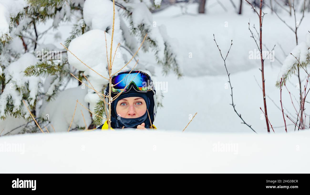 Jeune femme d'origine caucasienne dans un casque et des lunettes en plein air enneigé.Snowboardeur en vêtements d'hiver brillants.Vacances d'hiver dans la sk Banque D'Images