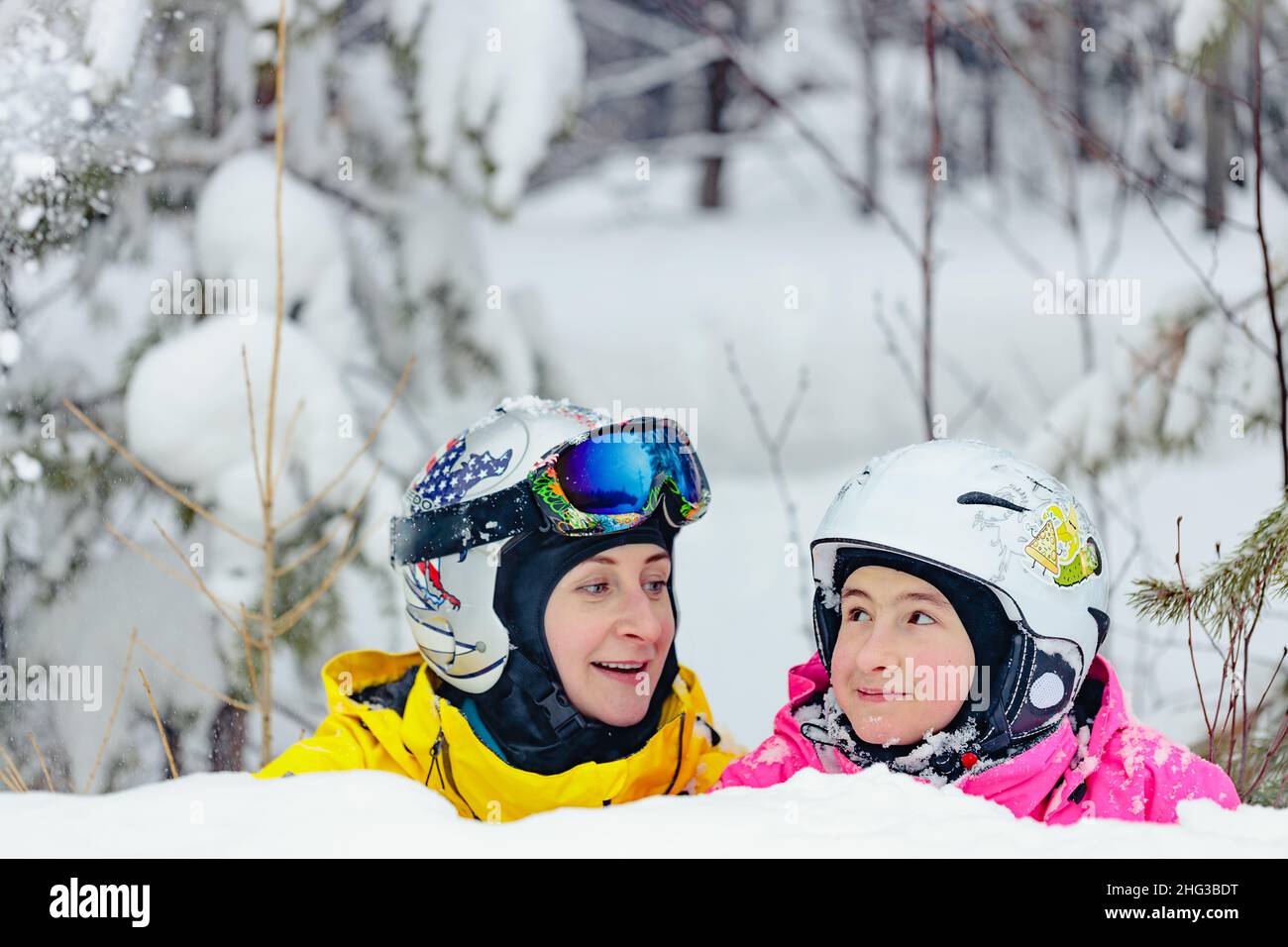 Une femme souriante et sa fille passent du temps ensemble au parc de surf des neiges.Maman et fille d'origine caucasienne dans un casque et des lunettes Banque D'Images