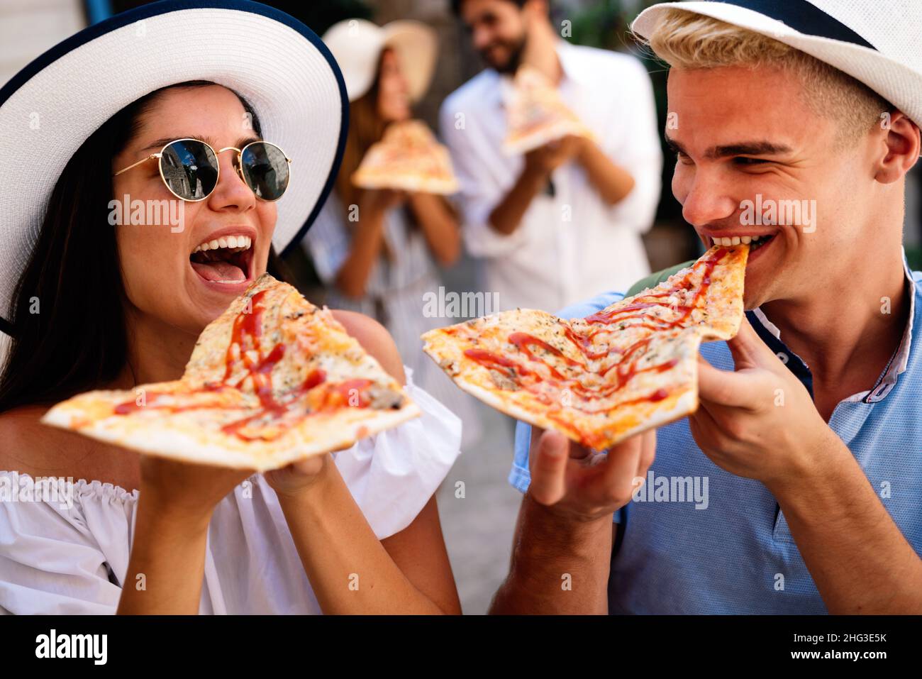 Un groupe heureux de personnes qui mangent de la pizza à l'extérieur, ils s'amusent ensemble. Banque D'Images
