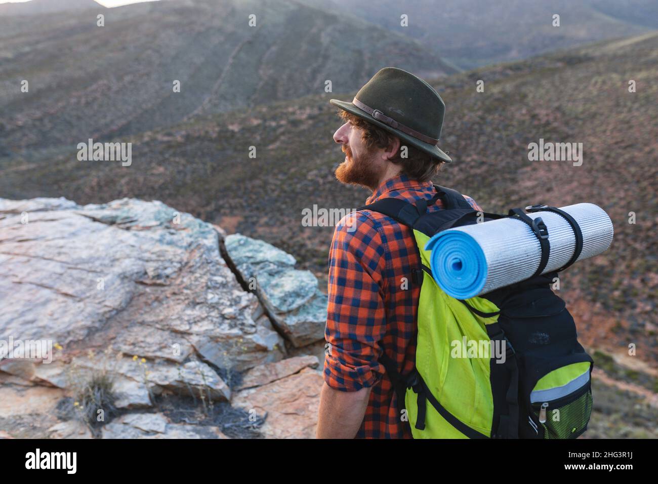 Jeune homme à barbe randonneur caucasien avec sac à dos portant un chapeau au sommet de la montagne Banque D'Images