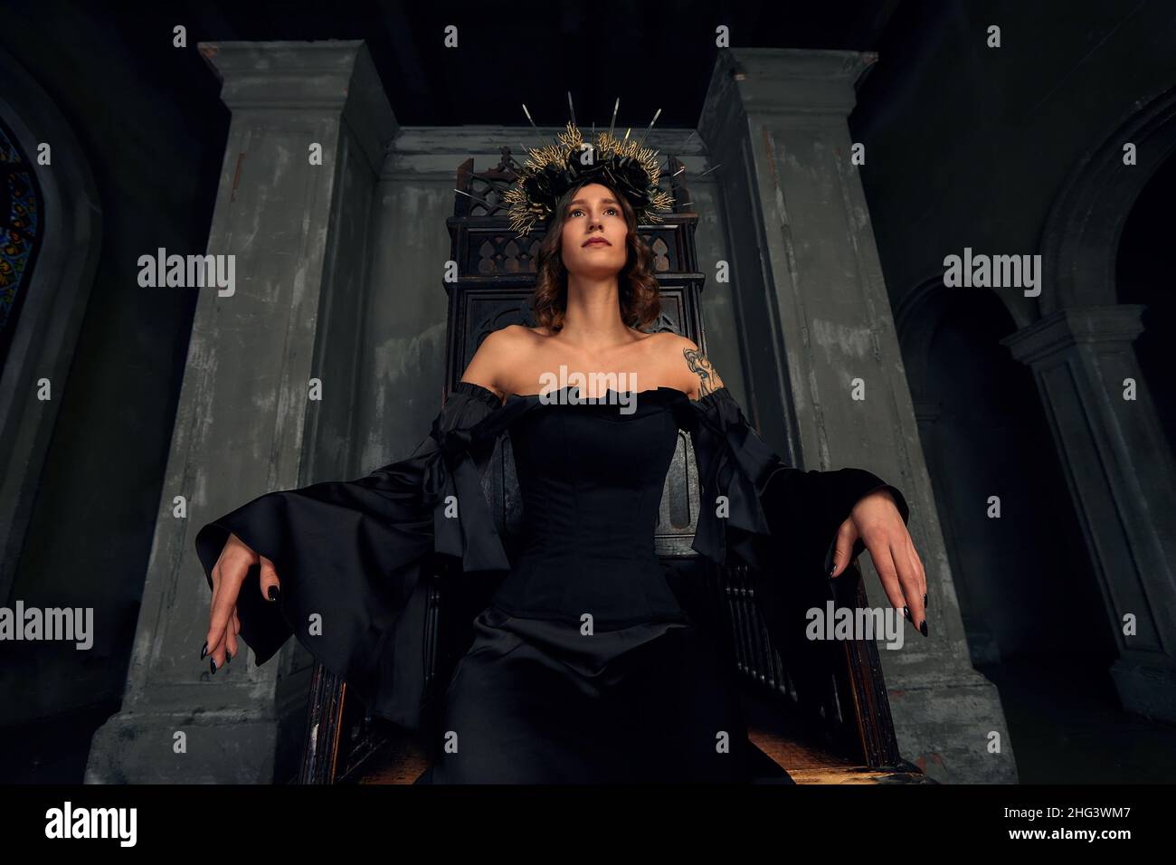 Portrait d'une belle jeune femme médiévale en robe noire dans une couronne élégante assise sur un trône.L'histoire du Moyen-âge. Banque D'Images