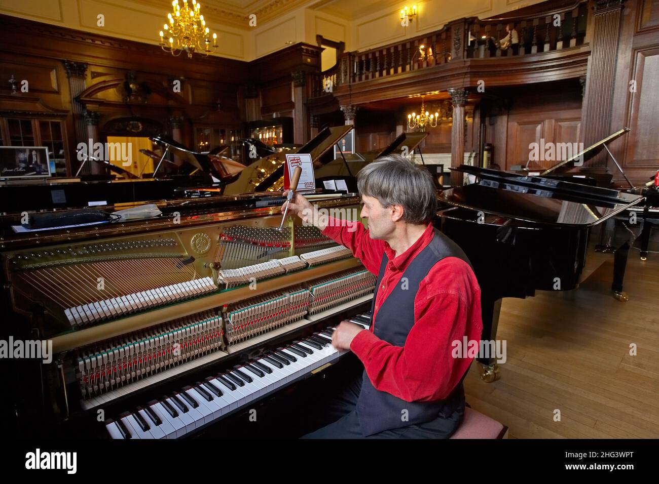 Piano Tuner est en cours de réglage d'un piano à queue à la main dans la boutique Yamaha à Londres . Banque D'Images