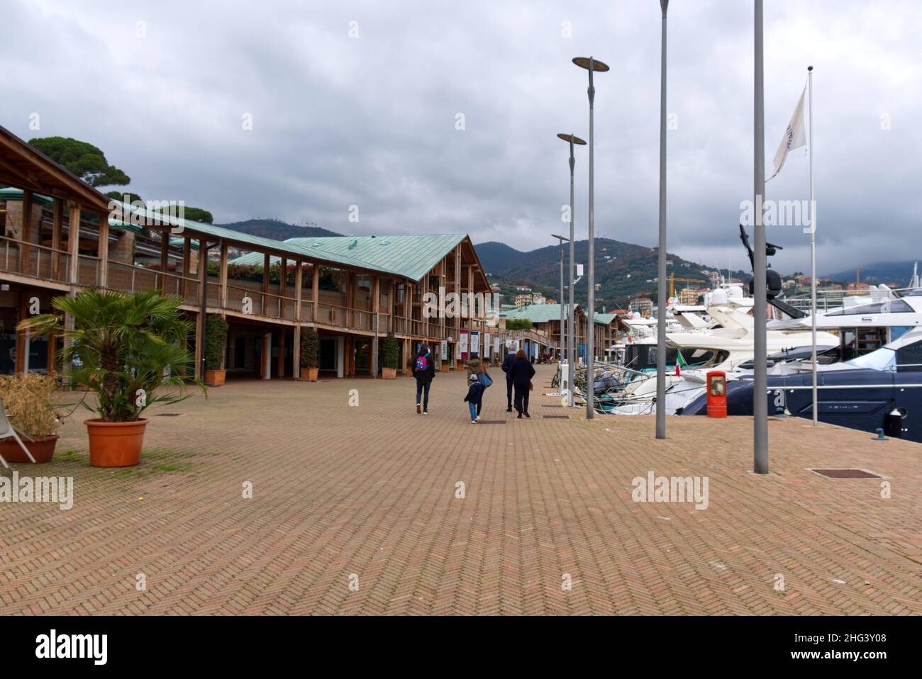 Une famille de touristes se promènent le long de la jetée du port de Varazze en hiver Banque D'Images