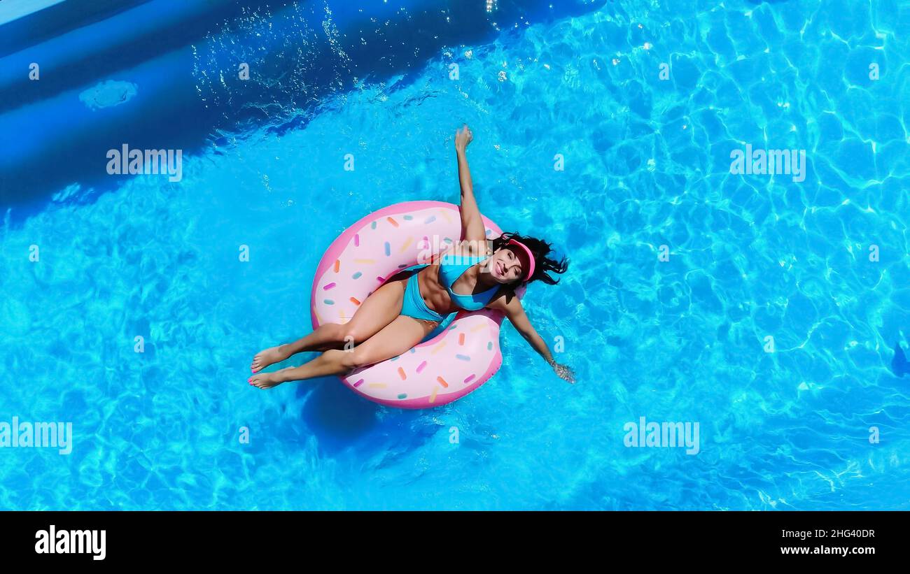 vue de dessus de la femme gaie nageant sur le ring de natation dans la piscine Banque D'Images