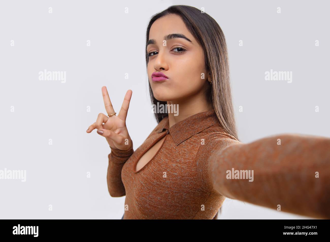 Jeune fille montrant le visage de canard et le geste de paix tout en prenant selfie Banque D'Images