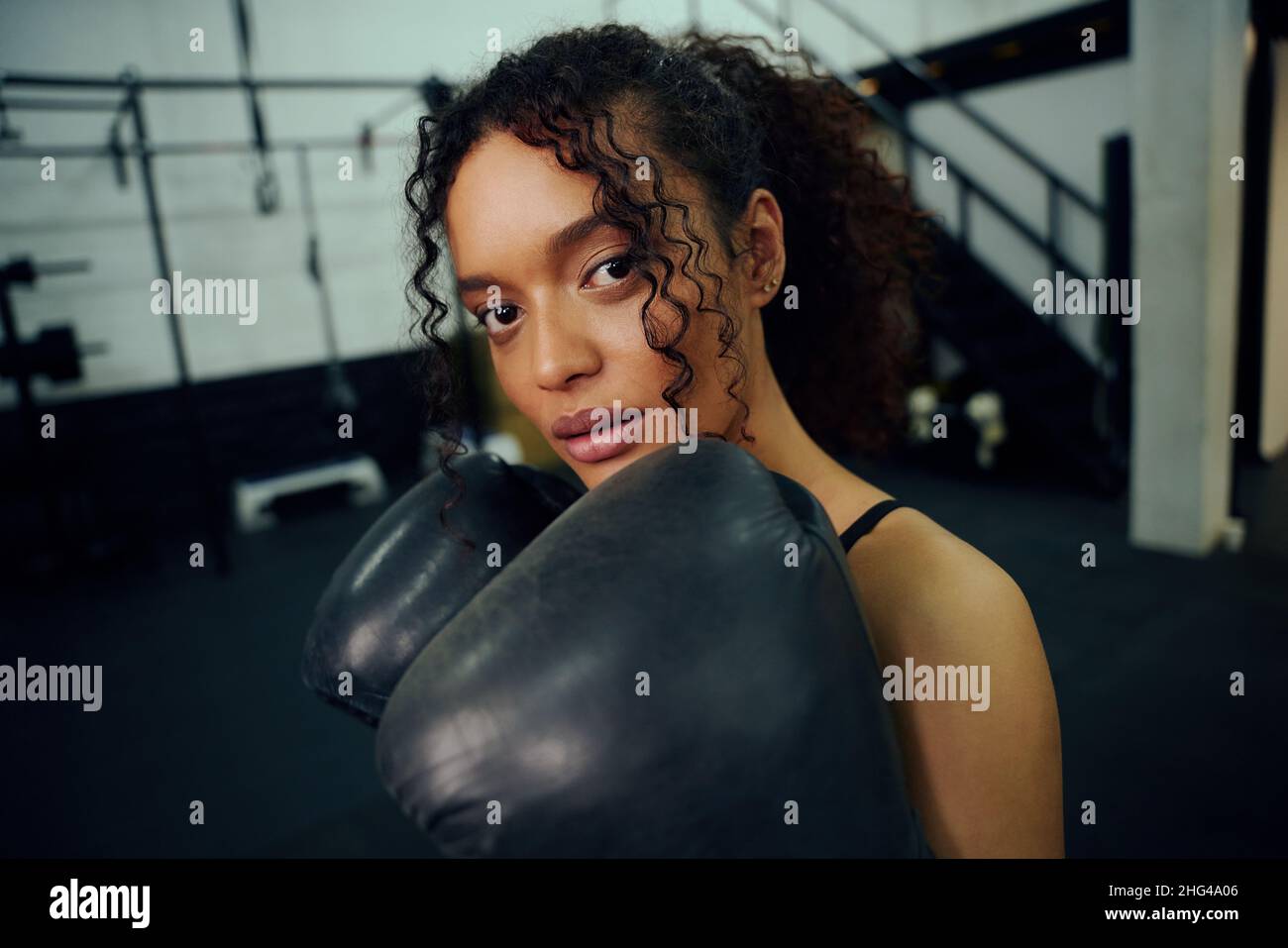 Entraînement de boxeur afro-américain à la salle de gym avec des gants de boxe. Femme de course mixte tenant des gants de boxe dans l'air. Photo de haute qualité Banque D'Images