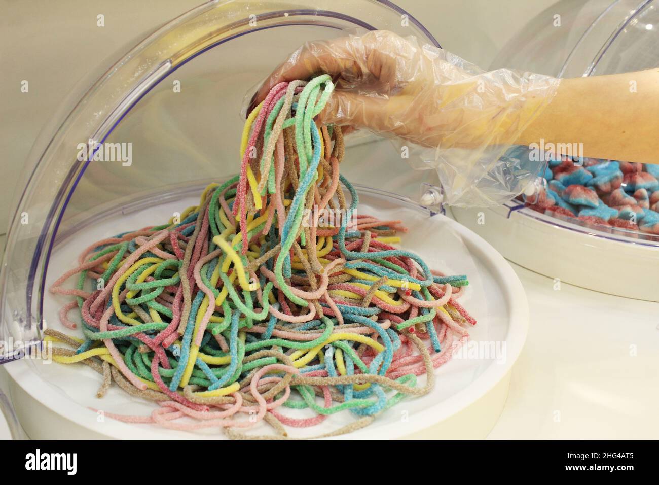 Une fille dans un gant jetable types mastiquer les bandes de marmelade de vers.Close-up, l'utilisation de gants jetables équipement de protection conforme à sanit Banque D'Images