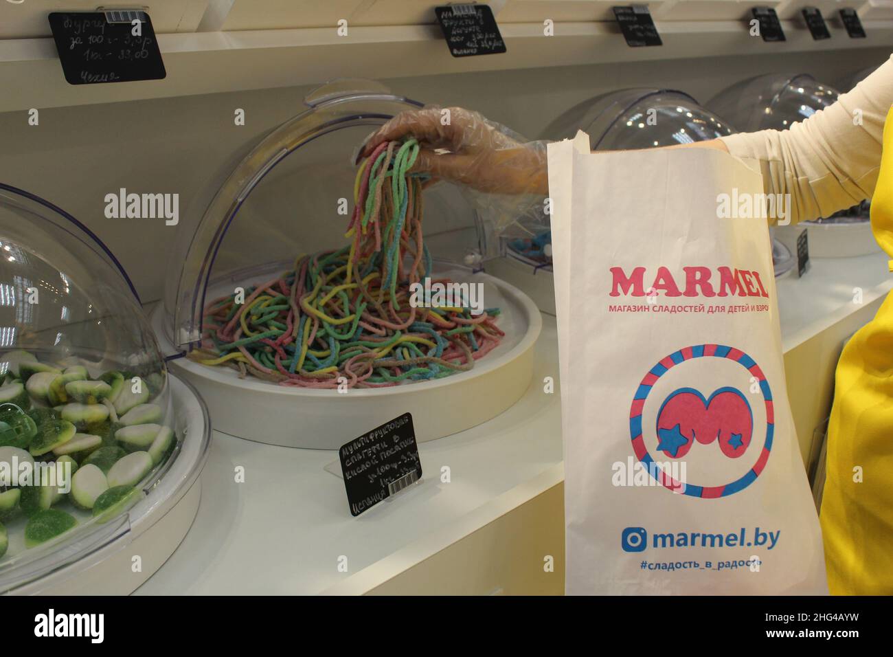 Une fille dans un gant jetable types mastiquer les bandes de marmelade de vers.Close-up, l'utilisation de gants jetables équipement de protection conforme à sanit Banque D'Images