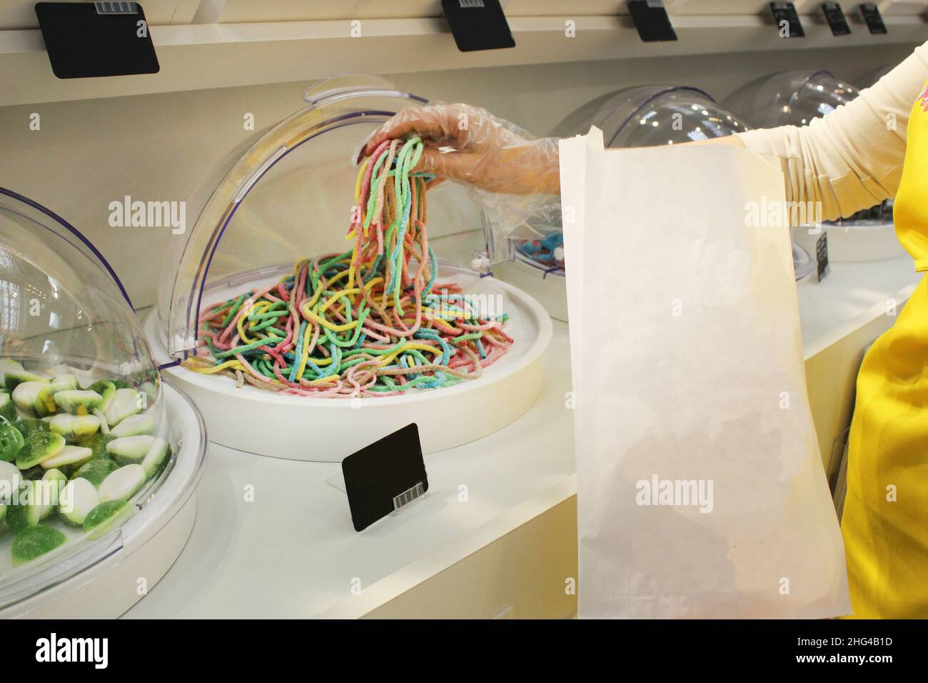 Une fille dans un gant jetable types mastiquer les bandes de marmelade de vers.Close-up, l'utilisation de gants jetables équipement de protection conforme à sanit Banque D'Images
