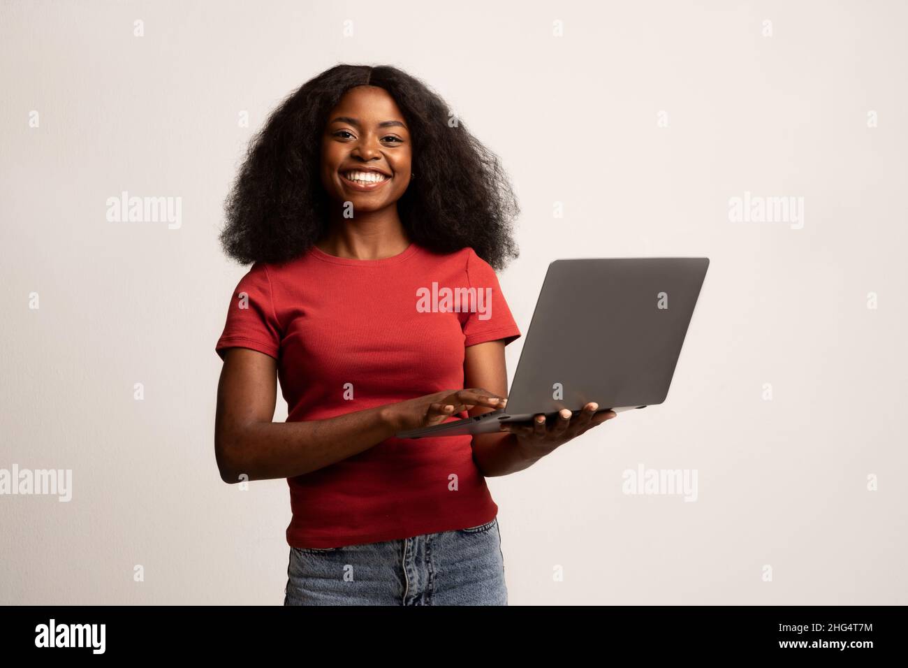 Travail à distance.Femme afro-américaine souriante tenant un ordinateur portable entre les mains Banque D'Images