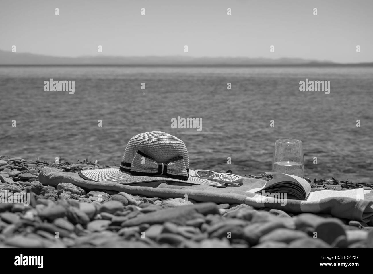 Concept de vacances d'été au bord de la mer avec serviette, chapeau et un livre, activité de loisirs à la plage en vacances Banque D'Images