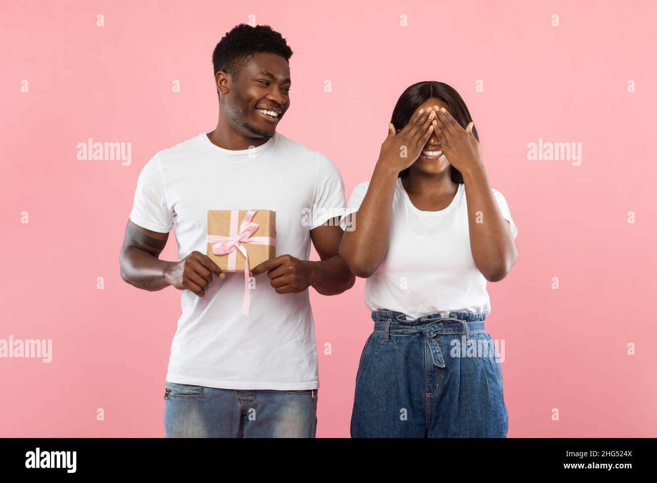 Joyeux homme noir faisant la surprise pour sa femme tenant boîte Banque D'Images