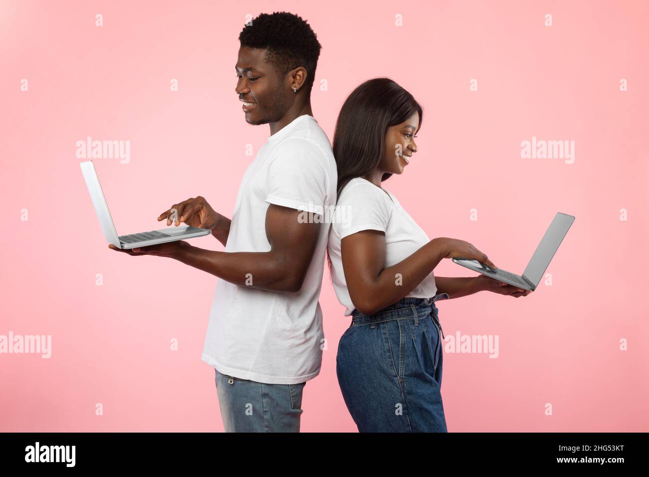 Couple afro-américain utilisant des smartphones, mur de studio rose Banque D'Images