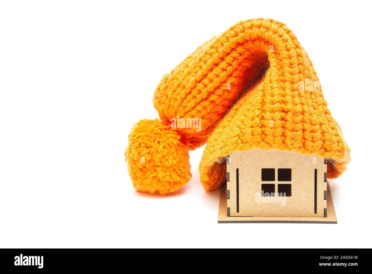 Chapeau pompon orange épais sur le dessus d'une maison de jouet isolée sur fond blanc.Chauffage à la maison pendant la saison d'hiver. Banque D'Images