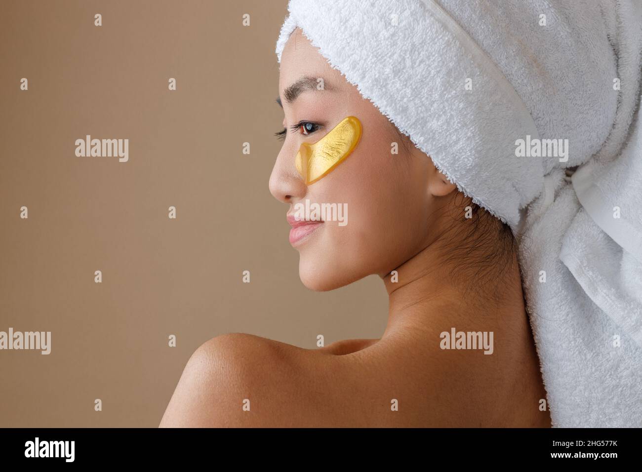 Jeune femme asiatique avec un timbre d'or sous les yeux debout en studio Banque D'Images