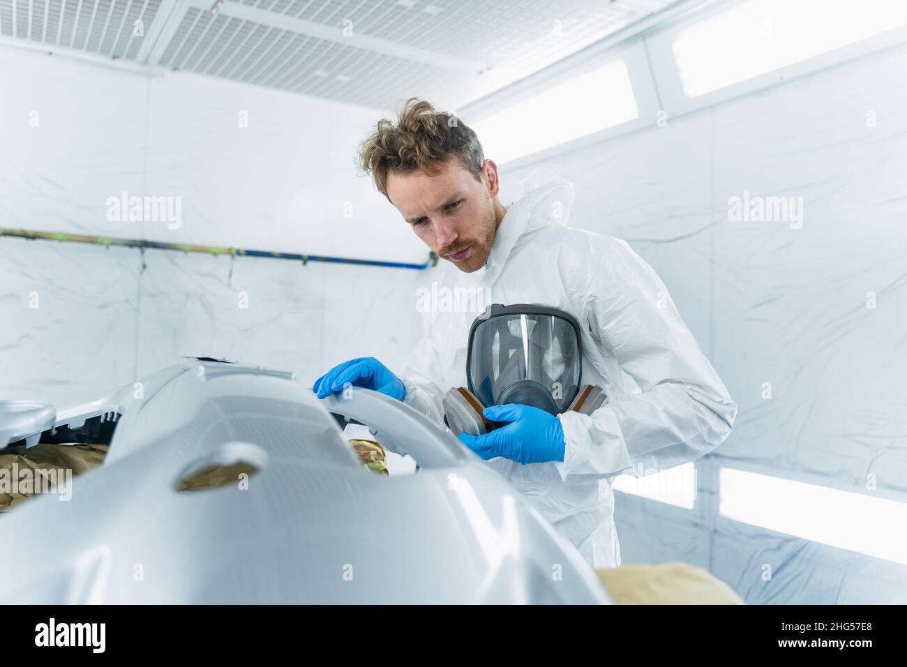 Peintre automobile travaillant dans une cabine de peinture.Processus de réparation de carrosserie du véhicule en service automobile Banque D'Images