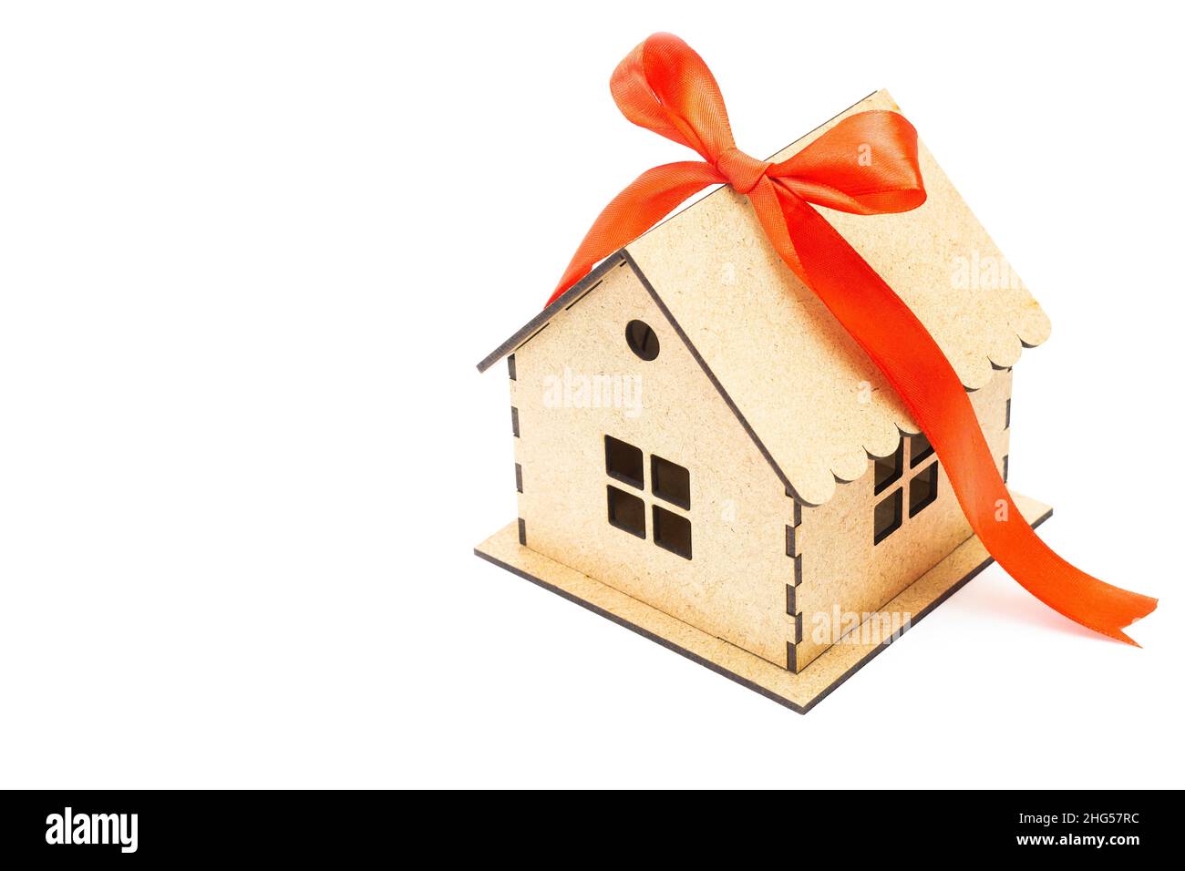 Modèle de maison avec un noeud en ruban rouge isolé sur fond blanc.Concept hypothécaire Banque D'Images