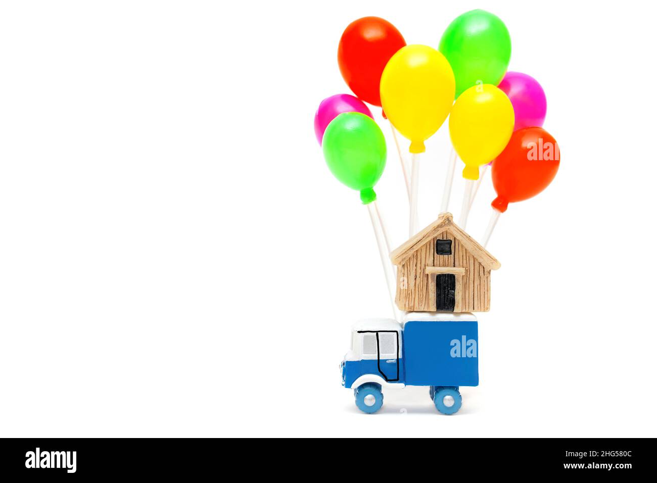 Camion de jouets avec un modèle de maison miniature et un groupe de ballons multicolores isolés sur fond blanc.Concept de service rapide. Banque D'Images