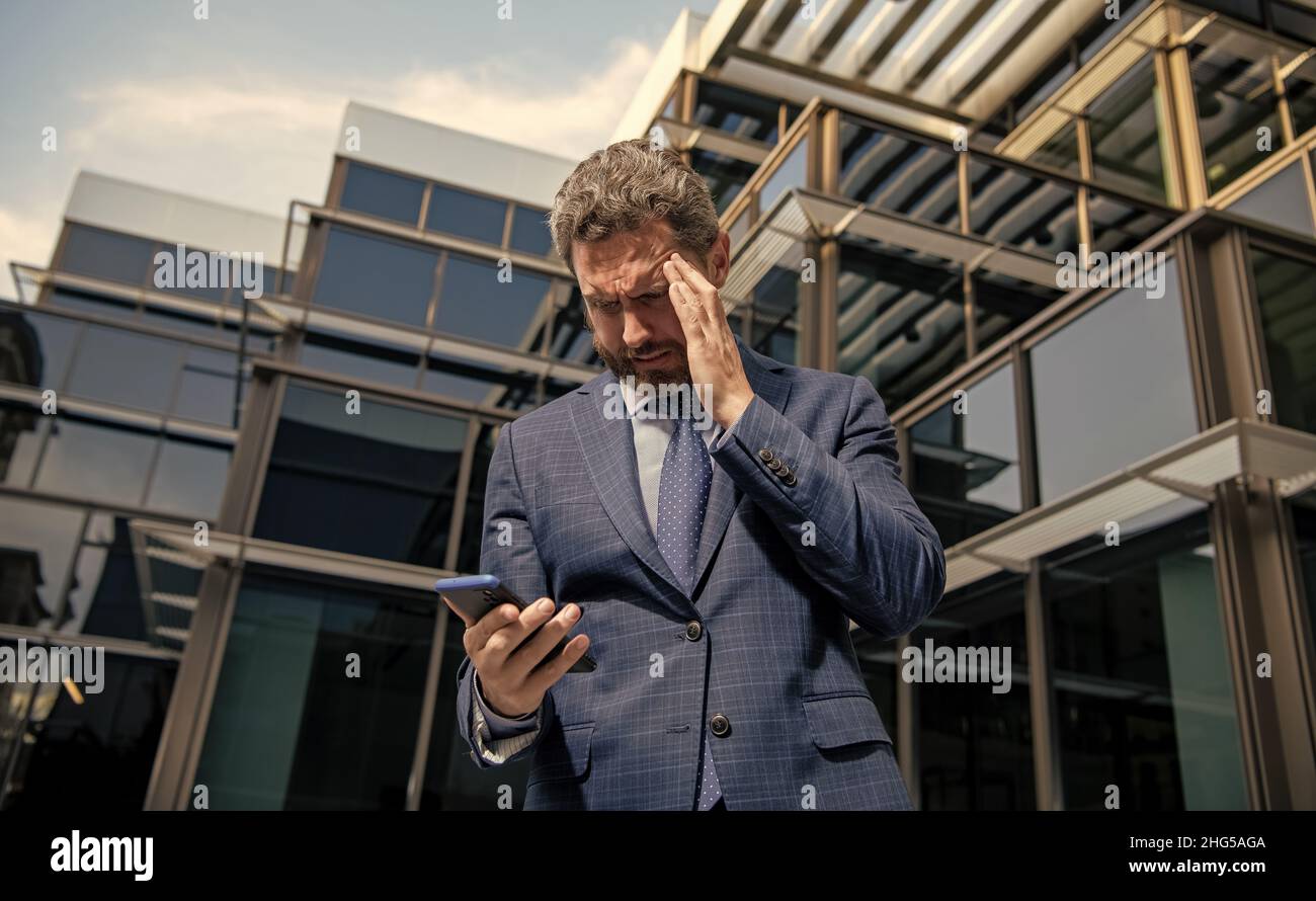 confondu homme d'affaires barbu en costume formel avec smartphone, anxiété Banque D'Images