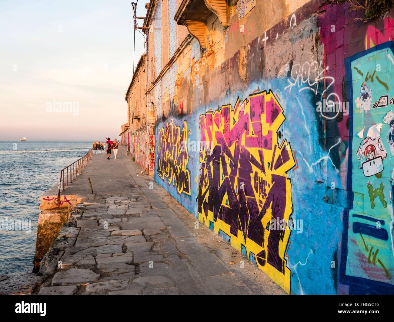 Lisbonne, Portugal - 18 octobre 2021 : graffitis et peintures murales dans la soirée au crépuscule sur des bâtiments abandonnés dans le quartier Almada de Lisbonne, au bord de l'eau o Banque D'Images