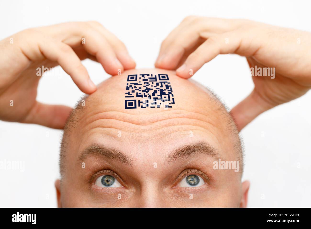 Un homme avec un code qr sur son front. L'homme regarde son code QR sur sa tête. Concept global de maîtrise de la population pour le contrôle et la gouvernance Banque D'Images