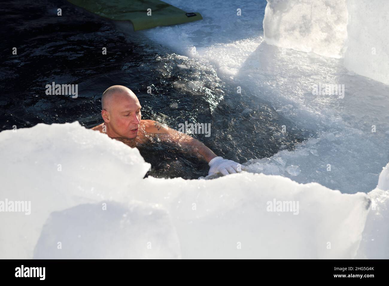 Homme qui respire profondément pendant que l'eau froide nage dans un trou de glace sur le lac Simcoe de la baie de Kempenfelt en hiver Barrie, Ontario Banque D'Images