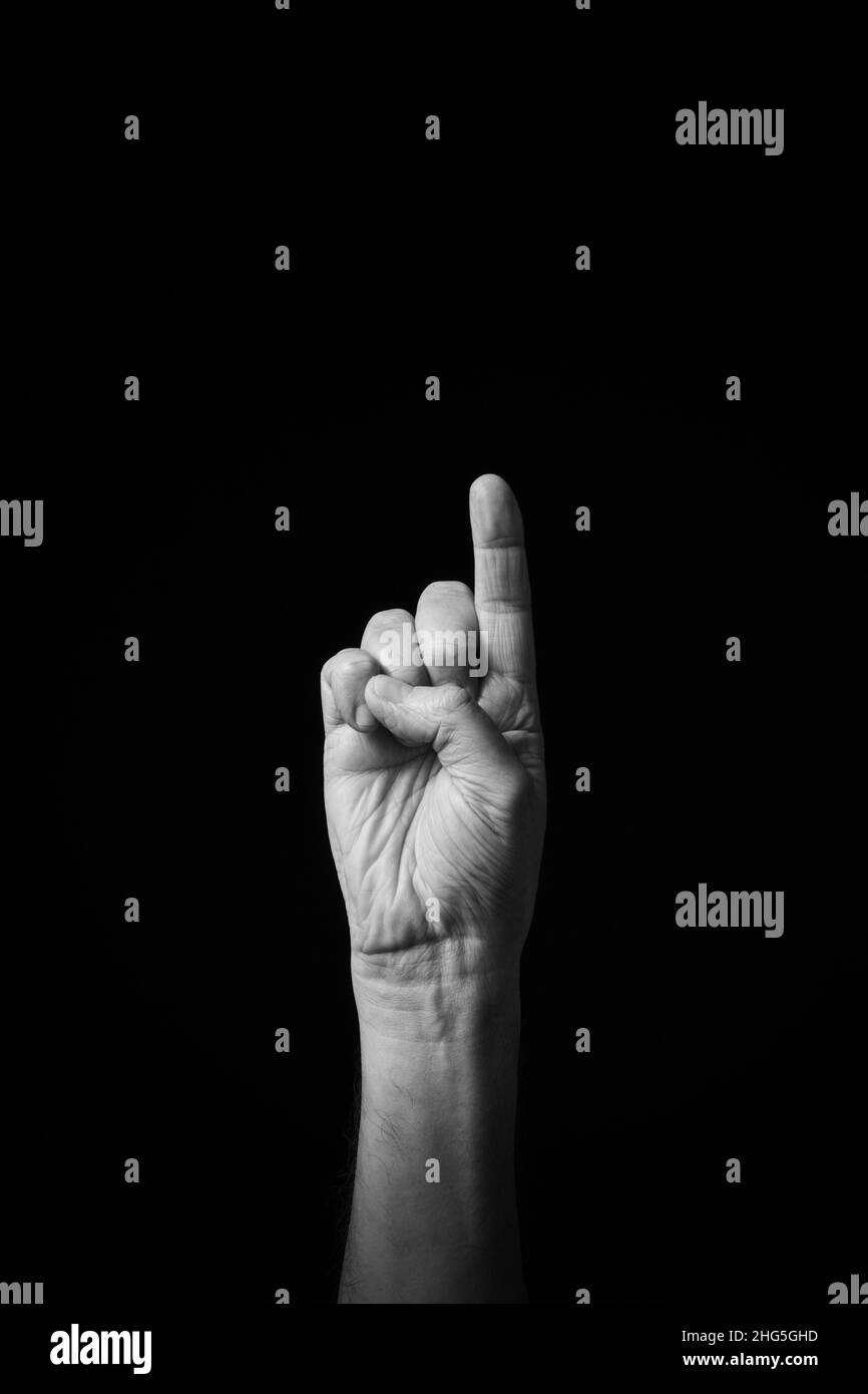 Image B+W dramatique de la main mâle dactylographiée CSL chinois langue des signes lettre I isolé contre fond sombre Banque D'Images