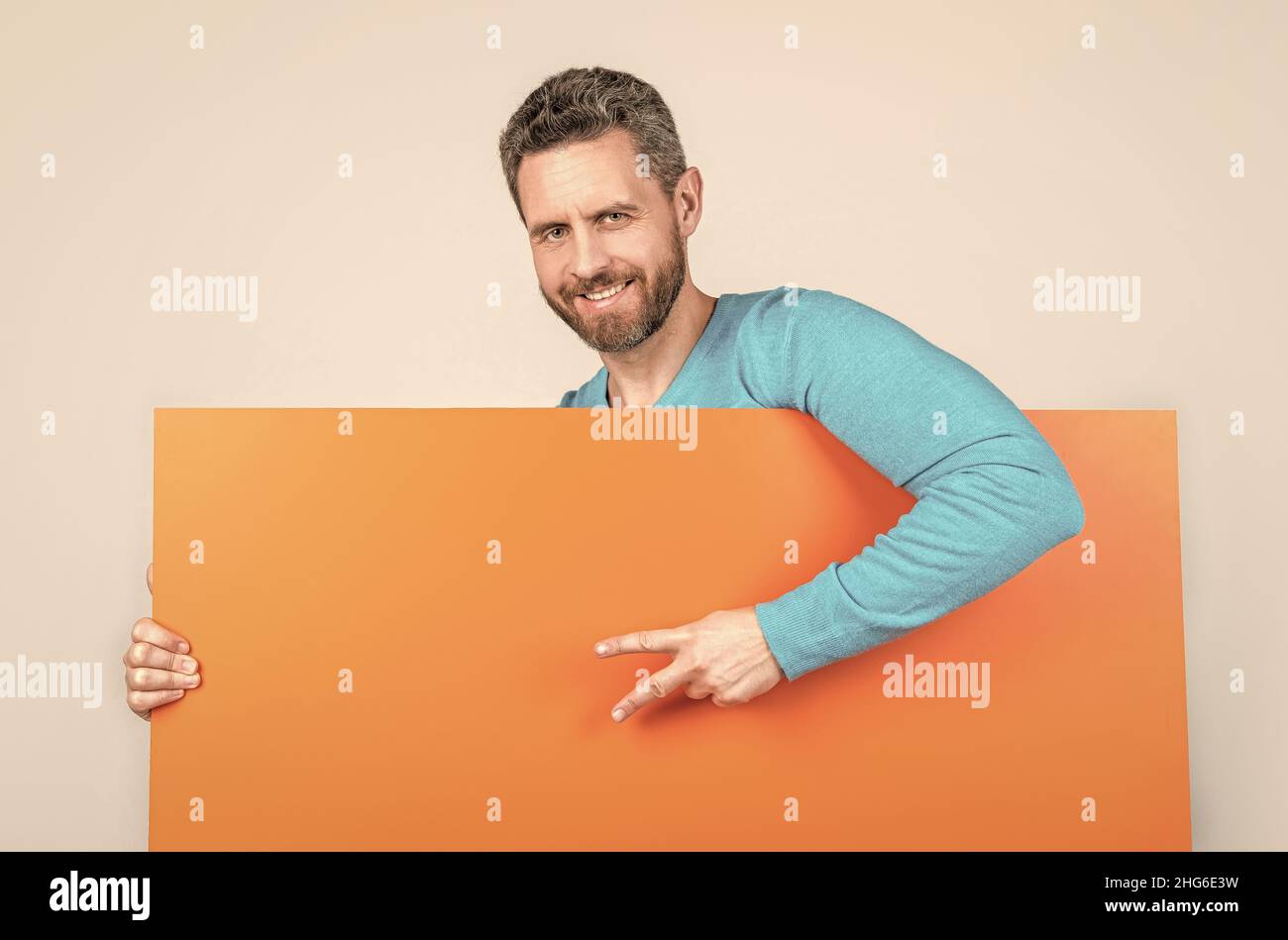 homme derrière une bannière en papier vierge avec un espace pour la copie de la publicité montre la paix geste, annonce. Banque D'Images