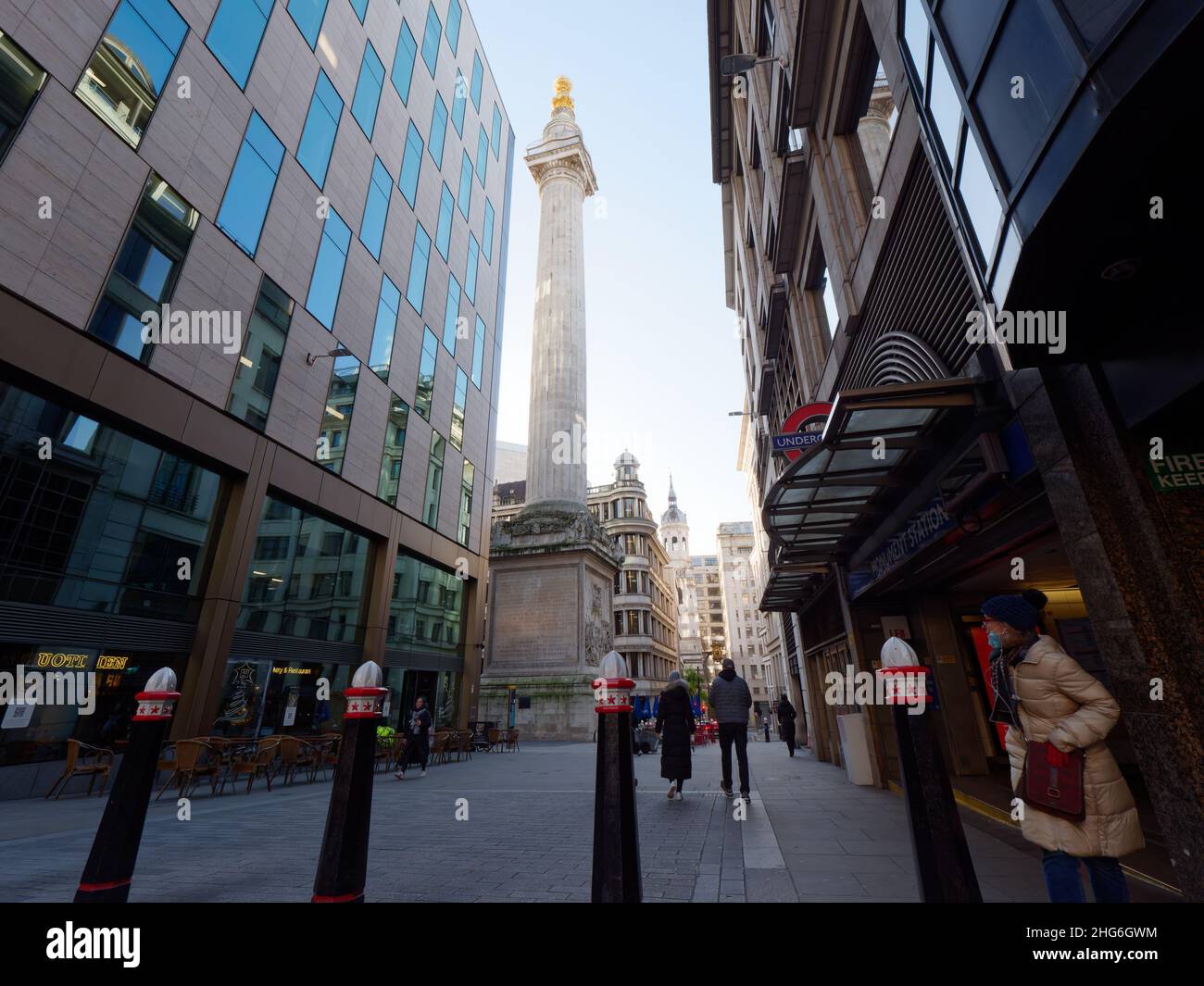 Londres, Grand Londres, Angleterre, janvier 5th 2022 : piétons à l'extérieur de la station de métro Monument pendant un matin hivernal avec le Monument derrière. Banque D'Images
